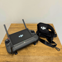 DJI remote control and strap on a wooden table.