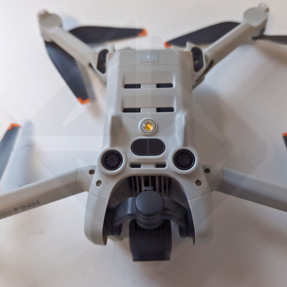 Drone gris avec hélices repliées sur table blanche.