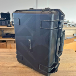 Valise de transport noire sur étagère en bois.