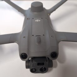 Drone gris avec caméras sur table blanche.