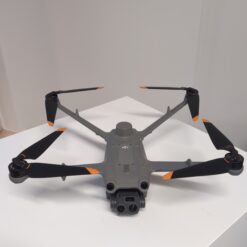 Drone gris avec hélices oranges sur table.