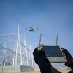 Opérateur pilotant le DJI Matrice 4T à la radiocommande lors d'une inspection de réseau électrique.