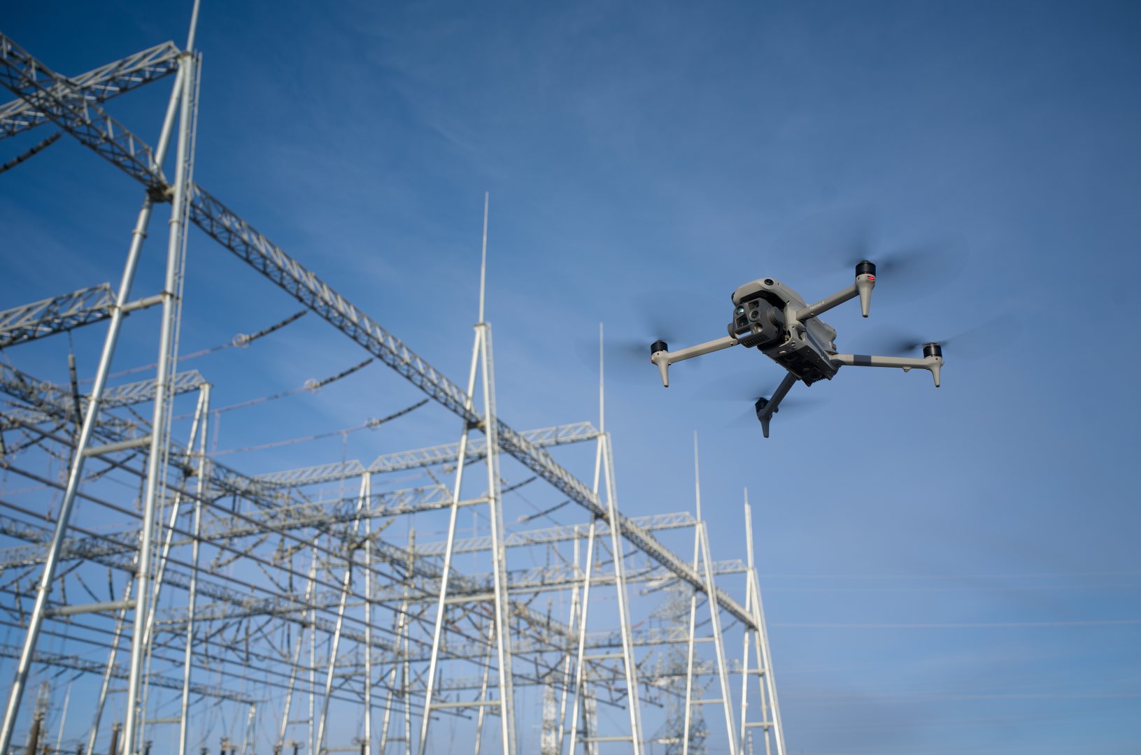 DJI Matrice 4T en vol au-dessus d'un poste électrique lors d'une inspection de réseau électrique.